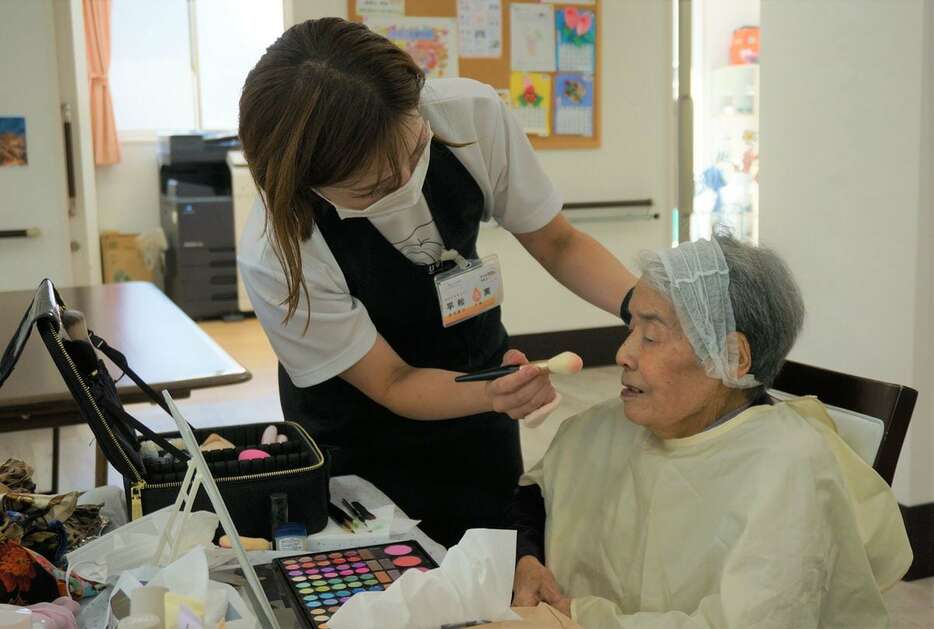 有料老人ホームの入居者に化粧を施す平松久実さん（左）。「目元はこの色がいい」など会話が弾んだ＝堺市美原区