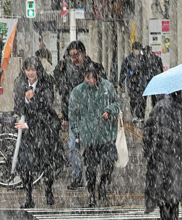 強く降りだした雪に本格的な冬の到来を感じながら、青森市中心部を行き交う市民＝18日午後2時46分、新町1丁目