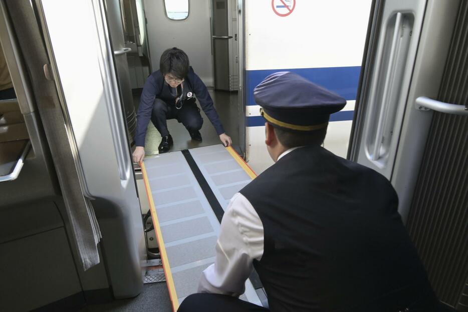 東海道新幹線の三島車両所で行われた訓練で、停電した列車と別の列車を渡り板でつなぐJR東海の社員＝7日午後、静岡県三島市