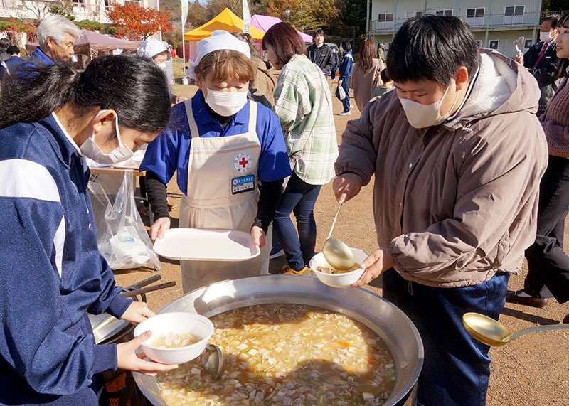 迫高キャンプで、炊き出しの豚汁を器に入れる大迫高生徒ら