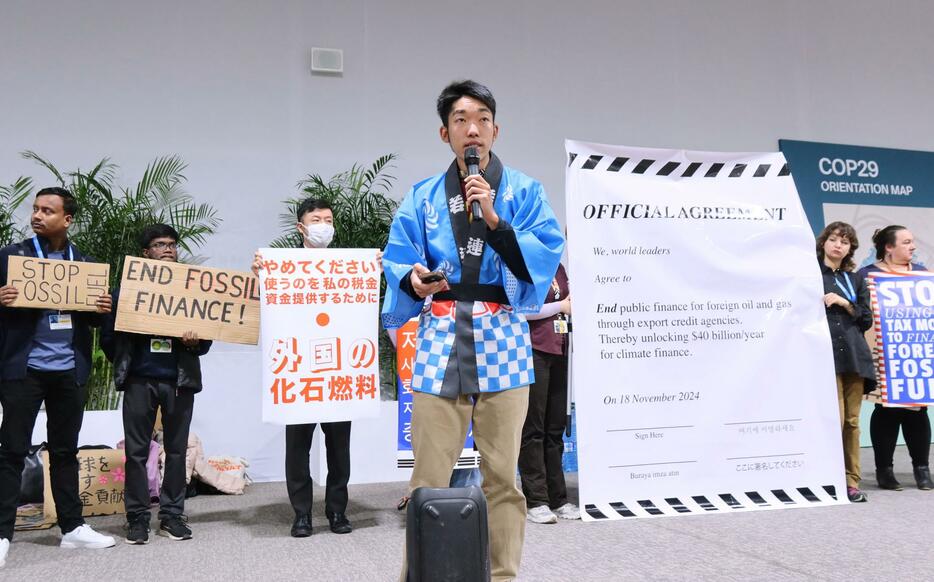 COP29の会場で化石燃料への公的支援停止を訴える高田陽平さん（手前）ら＝18日、アゼルバイジャン・バクー（共同）