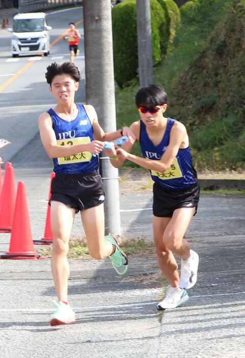 4区田中㊧からたすきを受け取る環太平洋大の5区松崎