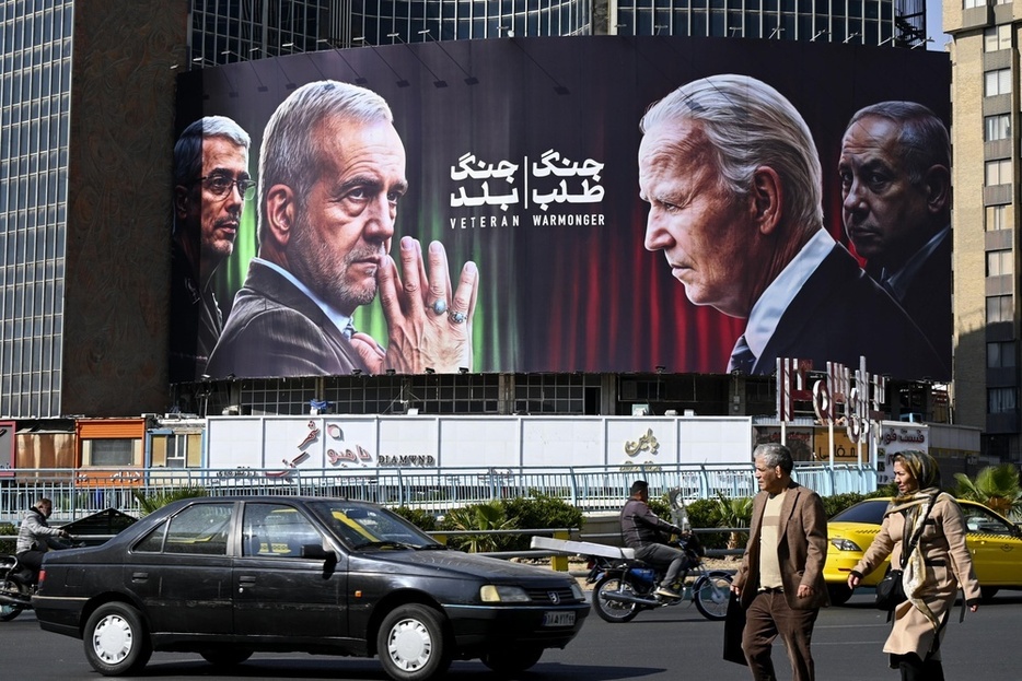 イランのペゼシュキアン大統領（中央左）やバイデン米大統領（同右）らの看板。バイデン氏とイスラエルのネタニヤフ首相（右端）を「戦争屋」と糾弾している＝10月29日、テヘラン（共同）