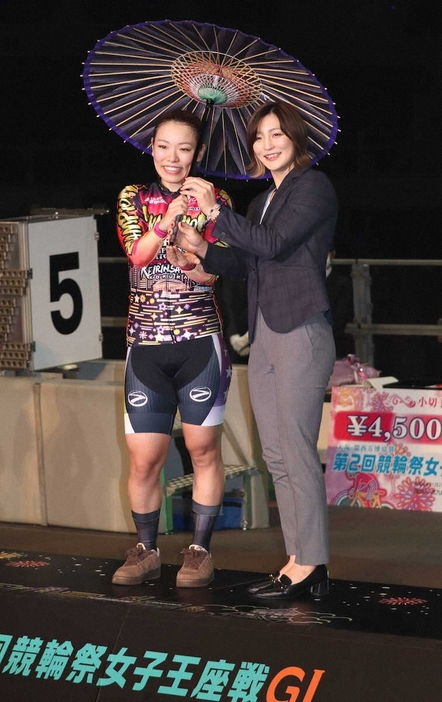 競輪祭女子王座戦を制し、パリ五輪柔道女子48キロ級金メダリストの角田夏実（右）と小倉織の和傘をさす佐藤水菜