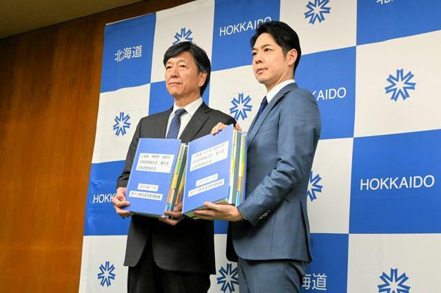 文献調査の報告書を掲げる鈴木直道北海道知事（右）と原子力発電環境整備機構（NUMO）の山口彰理事長=2024年11月22日、北海道庁