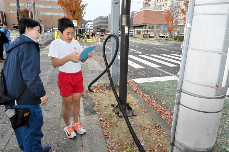 アプリを使って電柱を撮影する児童