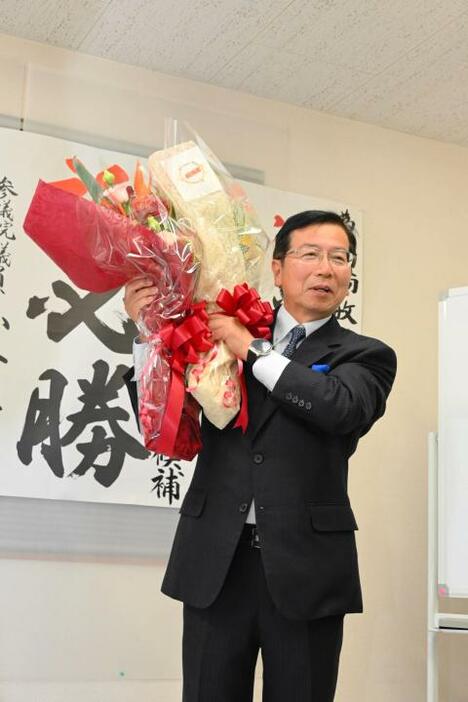 西条市長選で初当選し、花束を手に喜ぶ高橋敏明氏＝10日午後11時ごろ、西条市朔日市