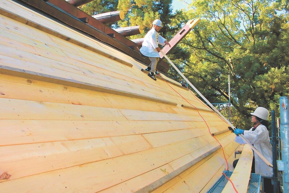 本殿の屋根に下地材のアテを敷く宮大工＝射水神社