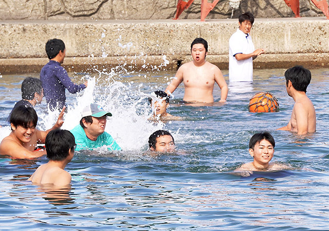 海水を浴び、海の実習が無事終了したことを感謝する生徒たち＝鶴岡市・加茂レインボービーチ