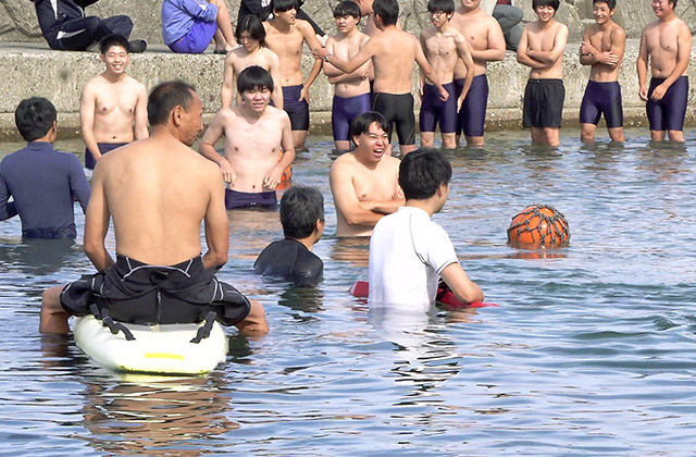 海水を浴び、海の実習が無事終了したことを感謝する生徒たち＝鶴岡市・加茂レインボービーチ