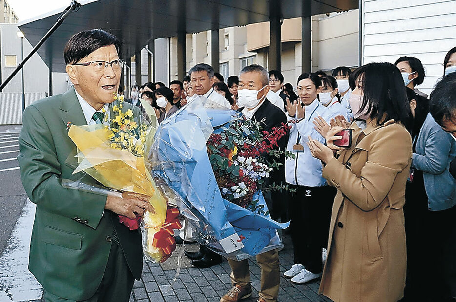 花束を手に退庁する林氏（左）＝氷見市役所