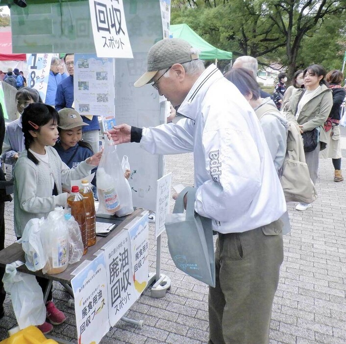 来場者から廃食用油を受け取る児童ら＝森の里公民館