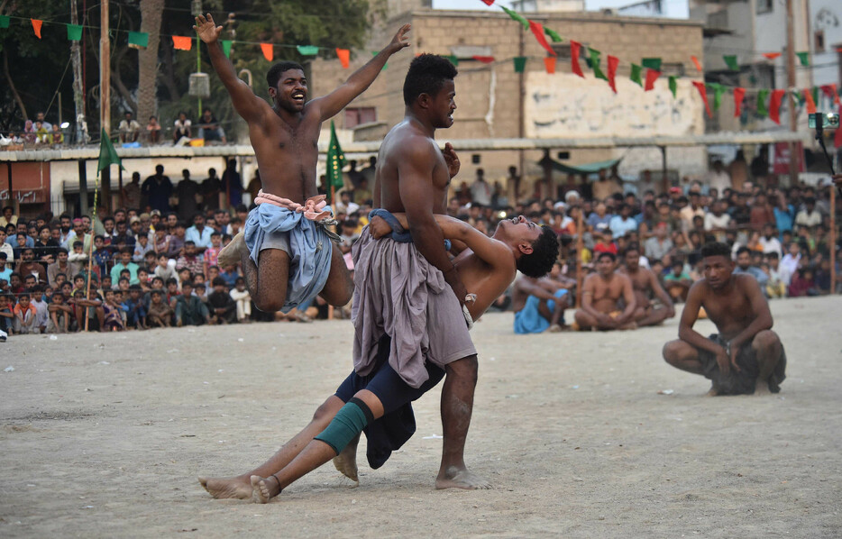 １０月３１日、パキスタン南部のカラチで開かれたパキスタン式伝統相撲の大会に出場した「力士」ら。相手の腰に巻き付けた布をつかみ、地面に投げ倒した方が勝ちとなる。