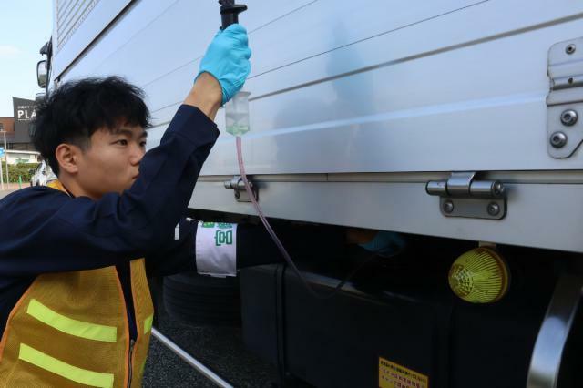 灯油や重油が混ざっていないか車両から燃料を抜き取る職員＝１９日午後、川南町の東九州自動車道・川南パーキングエリア