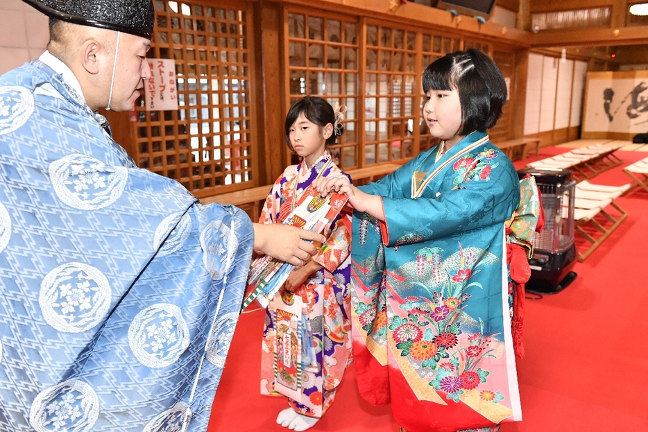 神事の後、千歳飴をもらう晴れ着姿の子どもたち＝16日、八戸市の櫛引八幡宮