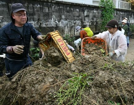 積もった土砂を片付ける国頭村消防や業者、ボランティアの人たち＝17日午後3時35分、国頭村比地（金城拓撮影）