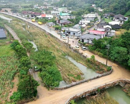 浸水被害を受けた集落のそばを流れる比地川。水面は草木に覆われている＝１２日午後２時過ぎ、国頭村（ドローンで撮影）