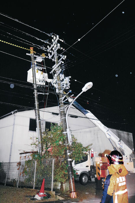 電柱の接触箇所を調べる作業員＝２３日午後９時、内灘町宮坂