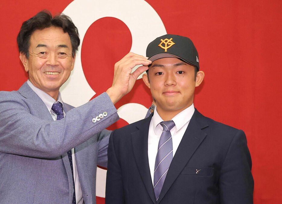 水野スカウト部長に帽子をかぶらせてもらう西川歩（右）（カメラ・今成　良輔）