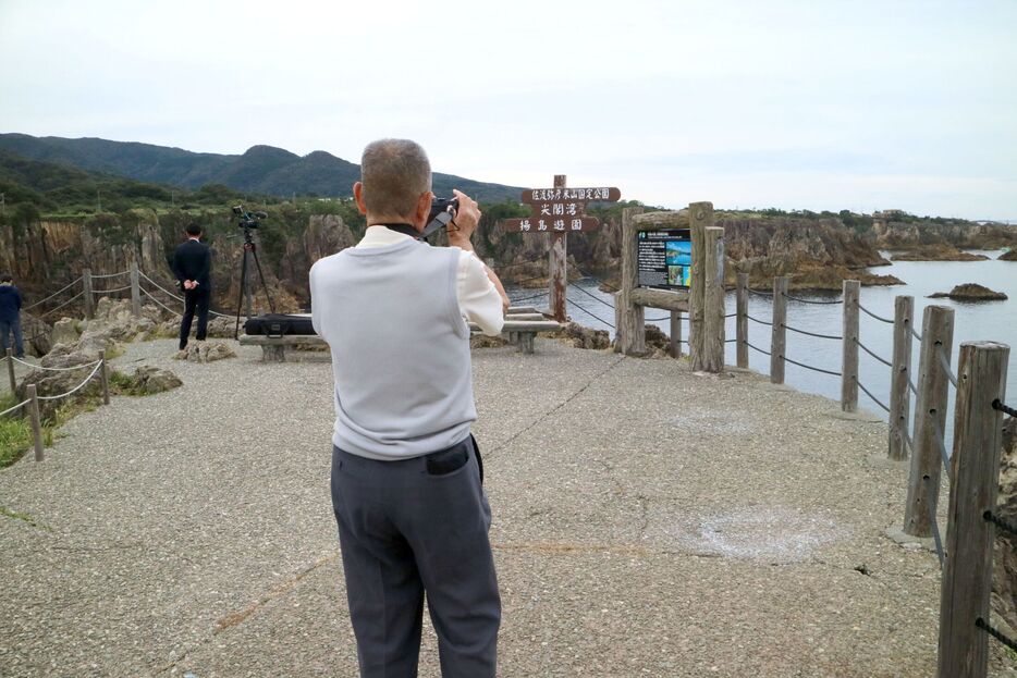 新潟県への「里帰り」で佐渡の尖閣湾を訪れた男性。趣味のカメラで古里新潟の風景を何枚も記録した＝佐渡市北狄