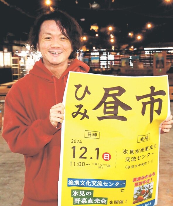 氷見市漁業文化交流センターで「ひみ昼市」をＰＲするポスターを手にする田中さん