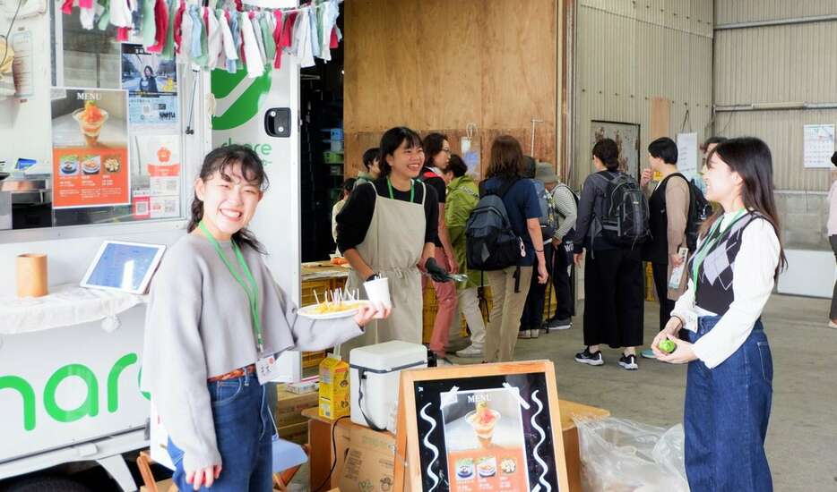 10月26日に開かれたイベントで、刀根早生柿をPRする学生ら＝奈良県天理市