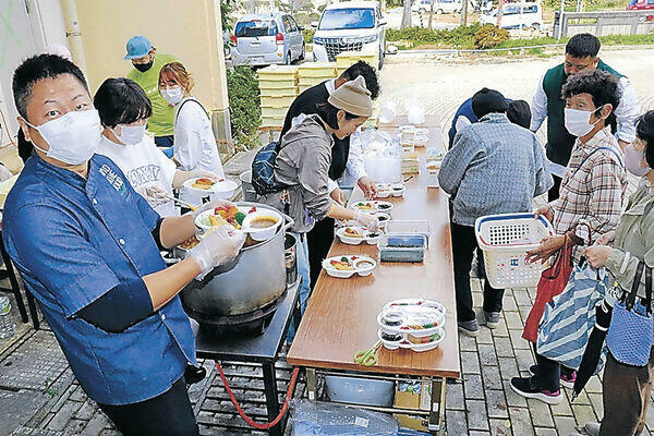 来場者にカレーを振る舞う冨成さん（左）=輪島市町野小