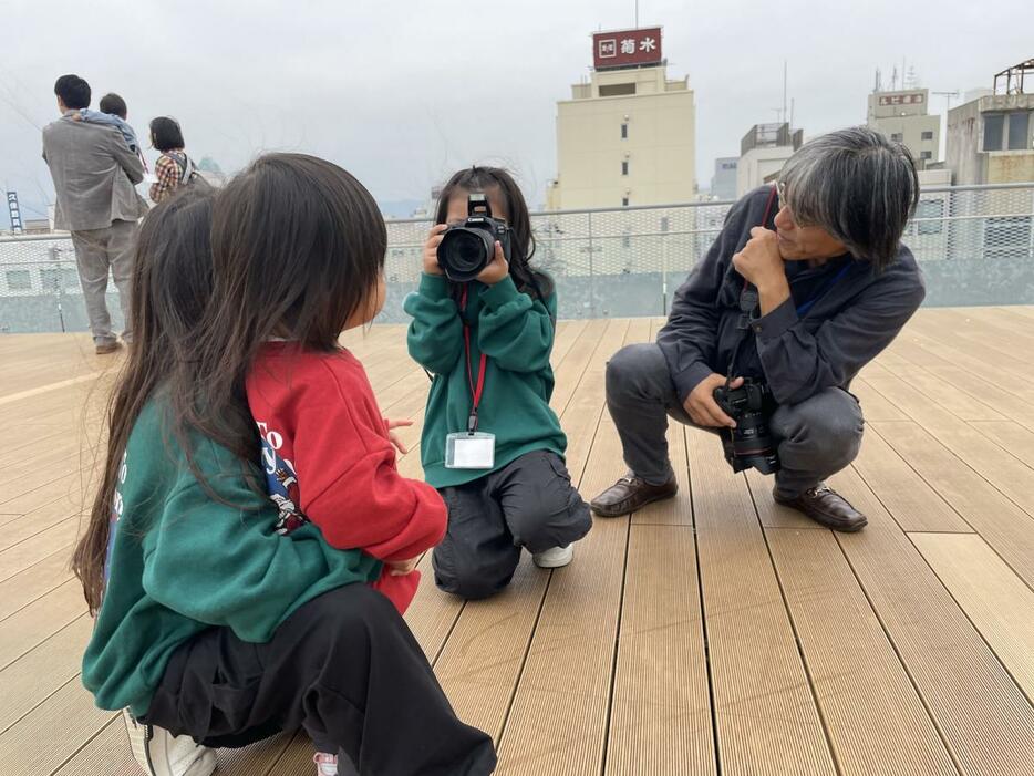 参加者の子どもがカメラを持つ場面。和田さんは、「脇をしめてカメラを固定するといいよ」と優しく助言し、子どもも嬉しそうに撮影していた