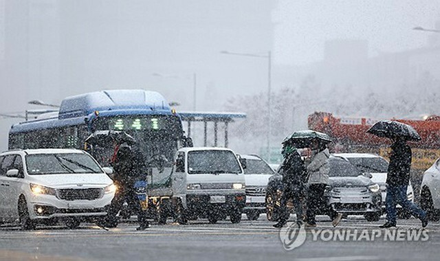 雪の中を歩く市民ら＝27日、ソウル（聯合ニュース）