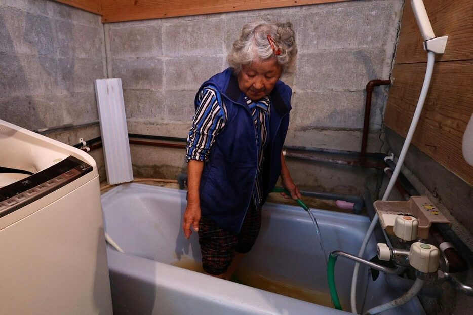 一部地域で水道が復旧し「ようやくお風呂に入れる」と浴槽を掃除する住民＝12日午後2時35分、大宜味村津波（大城直也撮影）