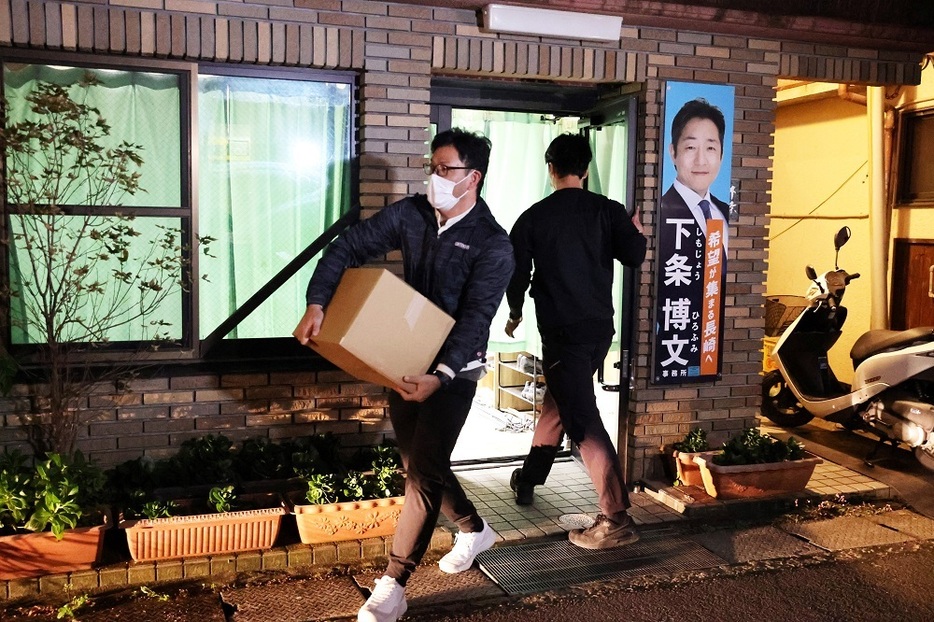 下条氏の事務所を家宅捜索し押収品を運び出す捜査員＝２０日午後５時５１分、長崎市文教町