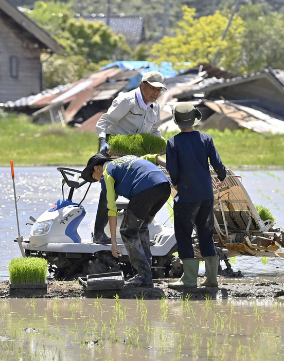 津波被害を免れた水田で、孫と田植えをする泊一夫さん（中央）＝5月、石川県穴水町甲地区