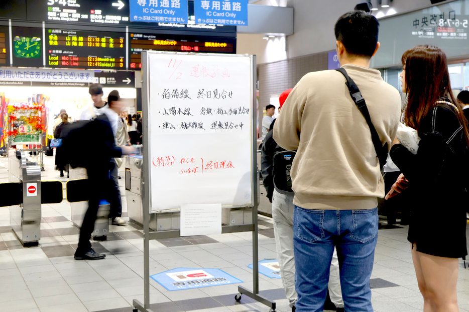 運行状況を知らせる掲示板に見入る駅利用者＝2日午後0時21分、JR岡山駅中央改札口