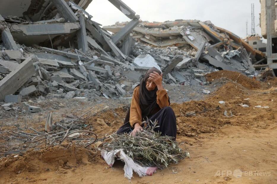 パレスチナ自治区ガザ地区中部ヌセイラートで、イスラエル軍の砲撃がやんだ後、破壊された建物の前で休憩する高齢女性（2024年11月29日撮影）。【翻訳編集】 AFPBB News