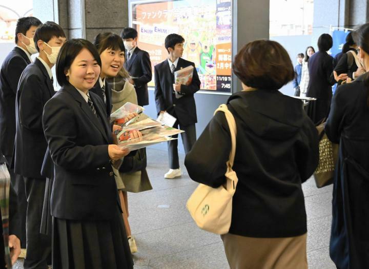 通勤・通学客にチラシを配り、乗車マナー向上を呼びかける高校生＝19日朝、伊予鉄道松山市駅