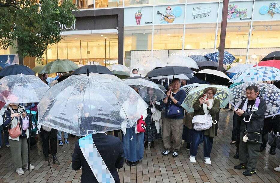 激しい雨が降る中、候補者の演説を聞く有権者＝2日午後、神戸市中央区