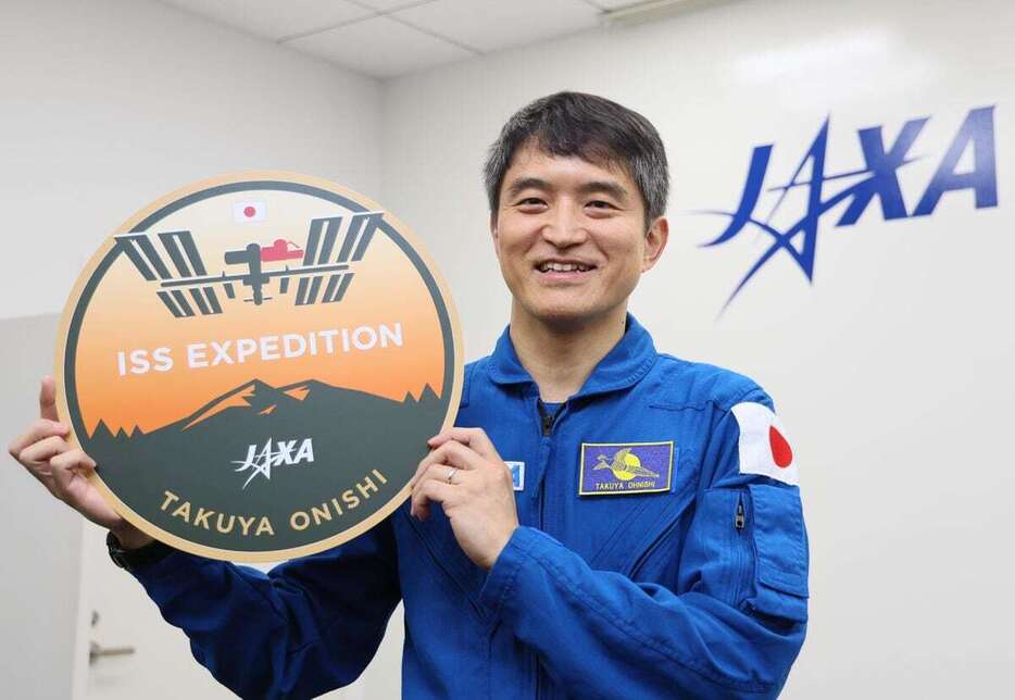 ミッションロゴを手に笑顔を見せるJAXAの大西卓哉宇宙飛行士＝27日午後、東京都千代田区（桐原正道撮影）