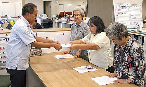 宮良部長（写真左）に申し入れ書を手渡す連絡会＝1日午後、市役所