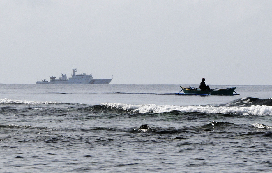 スカボロー礁周辺で停泊する中国海警局の艦船（左）と、操業するフィリピン人漁師の船＝2016年12月