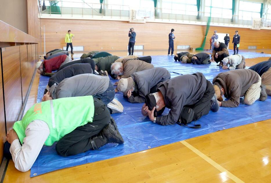 弾道ミサイルが発射された想定で身を守る姿勢を取る住民＝１１月１０日、上越市南城町３