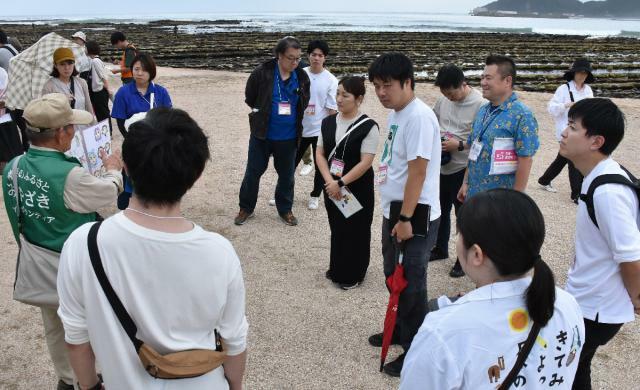 青島地域の活性化策を学ぼうとボランティアガイドの説明を聞く県内外のまちづくり団体関係者ら＝２日午後、宮崎市・青島