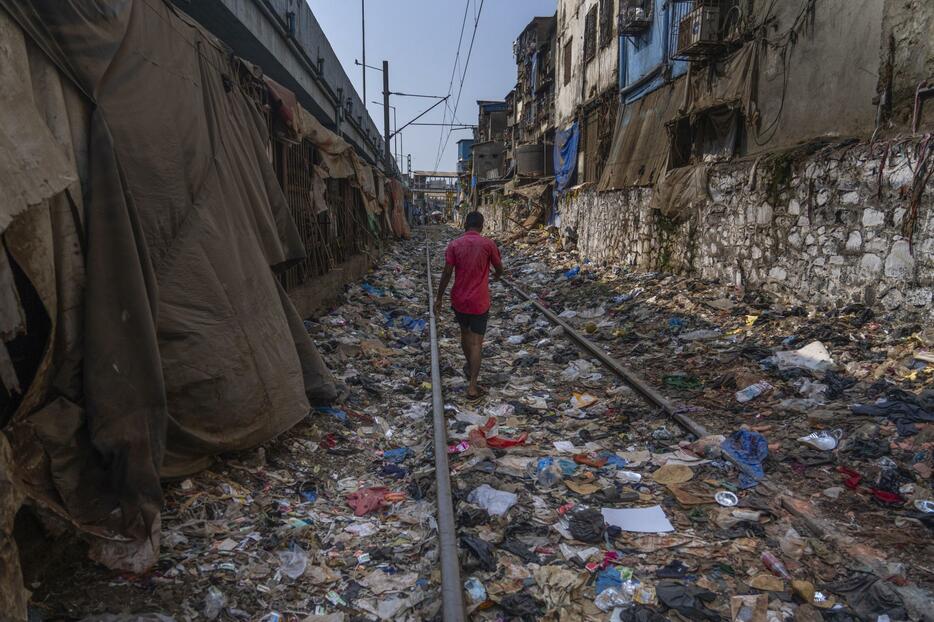 プラスチックごみなどが散乱した線路を歩く男性＝4月、インド・ムンバイ（AP＝共同）