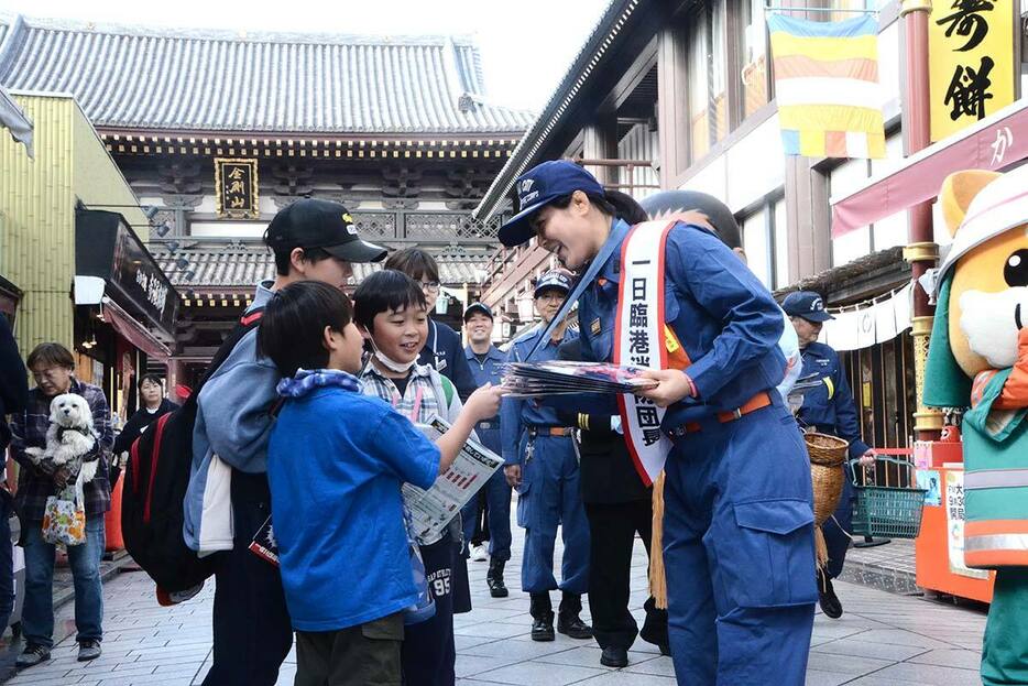 銅メダルを見せながら、火災予防を呼びかけた尾崎さん＝川崎大師平間寺周辺