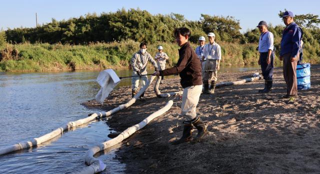 オイルフェンスを大淀川に張るなどした水質事故対応訓練＝６日午後、都城市都島町