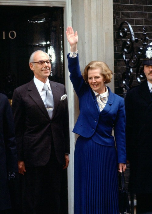 Getty Images 1979年、イギリス初の女性首相としての指名を受け、官邸前であいさつするマーガレット・サッチャー。鮮やかなブルーのスカートスーツに、同系色をリフレインした柄入りのブラウスをコーディネート。