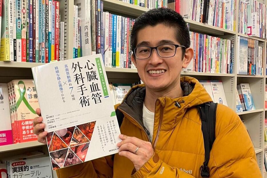 著書を手に笑顔を見せる心臓外科医の月岡祐介さん【写真提供：月岡祐介 心臓外科（@TsukiokaYusuke）さん】