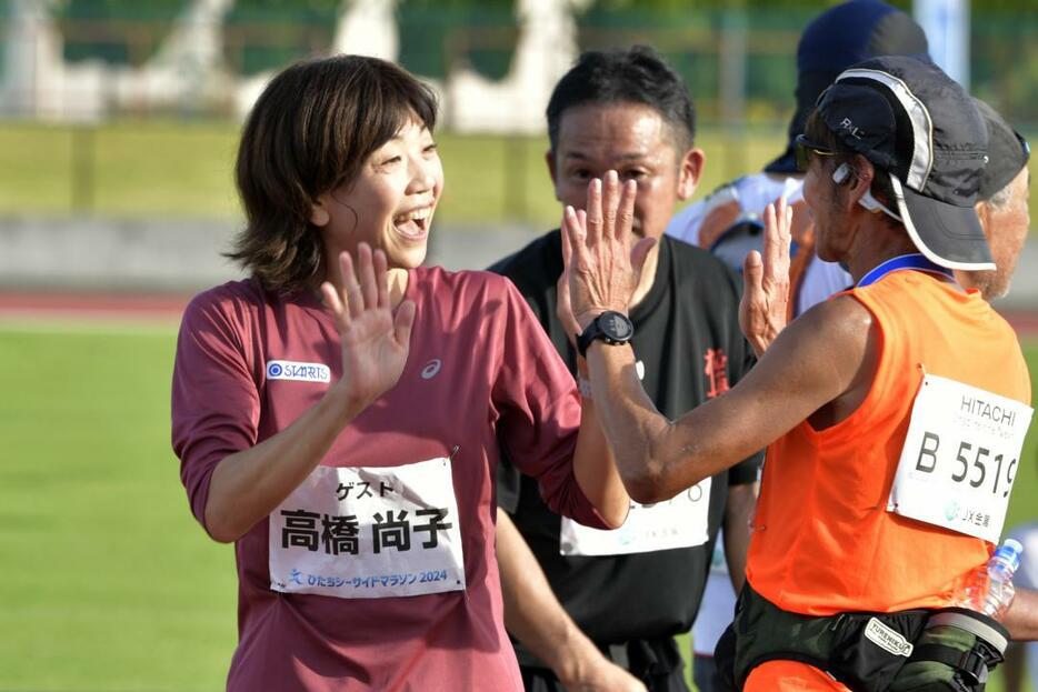 ゴールした選手と触れ合うゲストランナーの高橋尚子さん(左)=日立市民運動公園陸上競技場