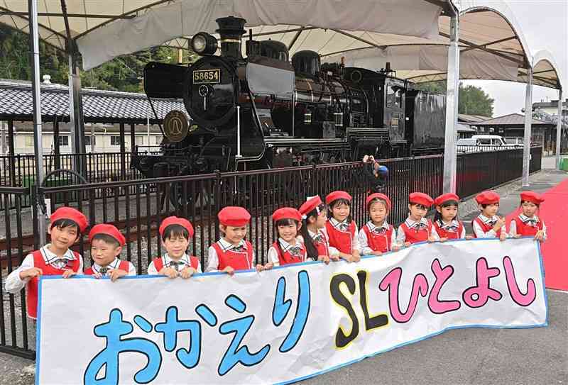 人吉駅でお披露目されたSL人吉。地元の園児たちが横断幕を手に歓迎した＝17日、人吉市（上杉勇太）