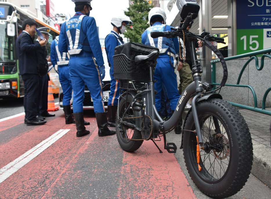 ペダル付き電動バイク「モペット」の取り締まりをする警察官＝１日午後、東京都新宿区