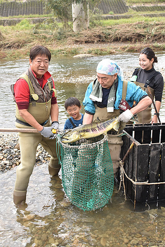 第1号のサケを持つ衣川組合長（11日午前10時ごろ）